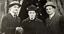 Photo noire et blanc de trois hommes en costumes avec des chapeaux melons.