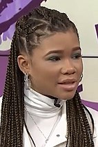 16 year-old girl with long, braided hair talking to something to the right.