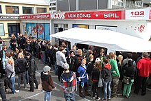 A crowd queues outside a comics shop and around tables.