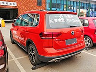 Rear-three-quarter view; car has promotional text written on it in Chinese and Latin characters