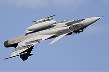 Jet aircraft with centerline external fuel tank during invert flight against blue sky