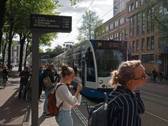 The tram is arriving at the tram stop Weesperplein where young women are waiting; free photo of Amsterdam city by Fons Heijnsbroek - street photography, Summer 2022.tif