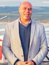 A white man wearing a suit, with a beach background