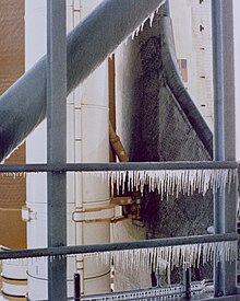 The underside of the orbiter wing and the SRB behind the structure of the service tower. The service tower has numerous icicles.