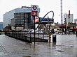 A white sign with a red circle on it and a blue rectangle on which is written "UNDERGROUND" in white letters all under a grey sky