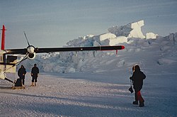 Pack ice of the Arctic Ocean accumulates off Cape Columbia. The Twin Otter airplane stands on the fast ice between the stacked pack ice (right) and the mainland