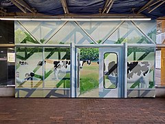 A mural of a fake doorway with cows grazing in a field