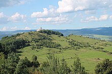 Suché louky, v pozadí hřebeny hor, věž Spišského hradu