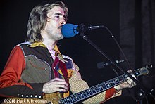 John Dawson onstage, singing and playing an electric guitar