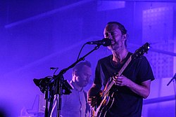 Thom Yorke playing guitar and Nigel Godrick performing