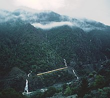 A Union Pacific freight train moving through the Feather River Canyon on a cloudy day, seen from on high.