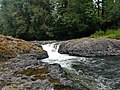 Small waterfall passing between boulders in front of some trees