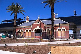 The old heritage station is placed in front of the new black rail bridge.