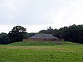 Earthy mud square building sitting atop an earthen mound