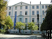 Vue d'ensemble d'un bâtiment scolaire à plusieurs étages, vu depuis la cour.