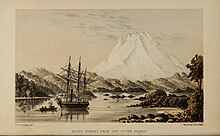 A white mountain rising over a forested bay with a ship