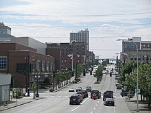 A city street lined with several buildings, street lights, and sets of traffic lights.