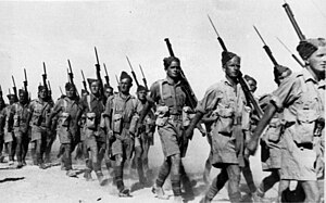 several men in desert uniform marching with rifles on their shoulders