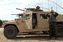 A soldier shades his eyes next to a vehicle