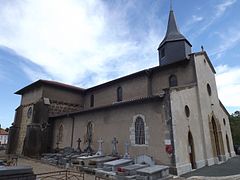 Photographie de côté d’une église, avec des tombes alignées sur son flanc droit.