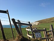 Skewing in a photograph taken from a car moving at 80 km/h (50 mph). Objects in the foreground, such as the fence and gate, have become skewed, while more distant objects in the background, such as the cliff, remain as normal.