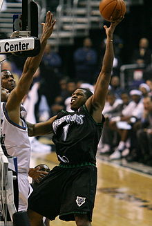 A basketball player wearing a black jersey with the number 1 on it shooting the ball.