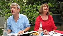 Axel Scheffler and Julia Donaldson sitting behind a table in a garden.
