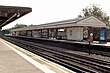 A grey railway platform with a railway track running down the middle and a rectangular, red sign reading "WHISTLE" in white letters