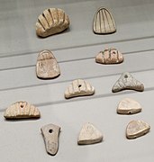 Jetons en argile aux formes diverses, incisés de motifs linéaires et de signes ronds.