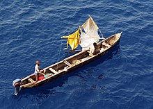 vue en plongée de deux hommes dans une pirogue longue et étroite