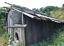 Weathered, gray redwood house with modestly pitched roof