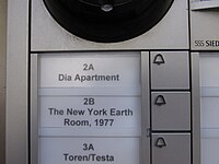 An close up view of a building buzzer system showing a button for "2A Dia Apartment" and "2B New York Earth Room".