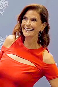 middle-aged woman of European descent, slim upper body, long brown hair, wearing red dress.