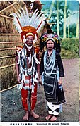 Carte postale : une photo montre un couple habillé en costume traditionnel devant une hutte.