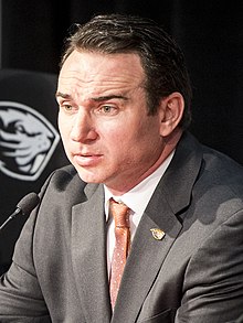 Jonathan Smith in a suit at a press conference.