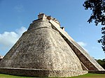 Stone pyramid with smooth surfaces and rounded corners. A staircase on one side leads to a structure at the top of the pyramid.