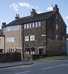 three storey stone-built, end-of-terrace cottage with six windows on the floor under the roof