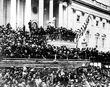 A large crowd in front of a large building with pillars.