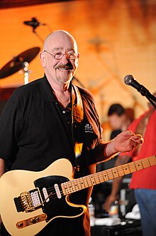 Mason smiling with a guitar slung over his chest