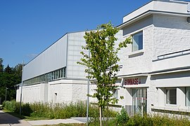 Grand bâtiment en construction avec pierre restaurée et bardage métallique.