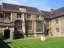 A courtyard of a set of stone buildings with large windows.