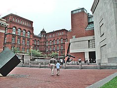 Raoul Wallenberg Place Entrance of USHMM. Three large façades made of brick and limestone. In the foreground a black modern art statue.