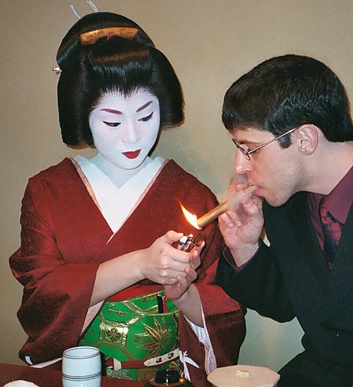 A geisha lights a client's cigar