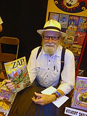 photographie couleur de Gilbert Shelton montrant une bande dessinée avec sa création Wonder Wart-Hog en couverture