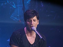 Young man in black shirt, singing into a microphone