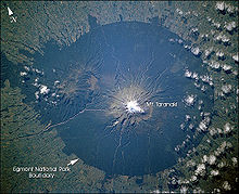 Egmont National Park auf einer Satellitenaufnahme der NASA von 2002. In der Mitte der Gipfel des Taranaki. Der Rand des dunkelgrünen Bereichs um den Gipfel markiert die Grenze des Parkes zum umgebenden Farmland