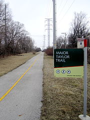 View down a bike trail, with a sign saying "Major Taylor Trail" on the right in the foreground