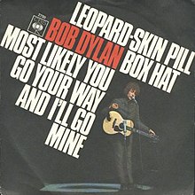 Single cover with the song titles in large text and Bob Dylan standing, holding an acoustic guitar