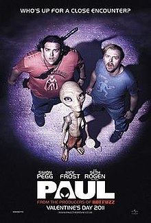 Two men and a short thin grey alien, all lit up by a spotlight