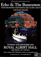 An poster advertising a concert with a black background and a picture of a circular building. Superimposed on the picture is a rowing boat with four men; two men are stood side by side at the back of the boat each holding an oar, the third man is sat in the centre of the boat and the fourth man is leaning over the front of the boat with his hand in the water. White text is on the poster at the top and the bottom giving details of the concert.
